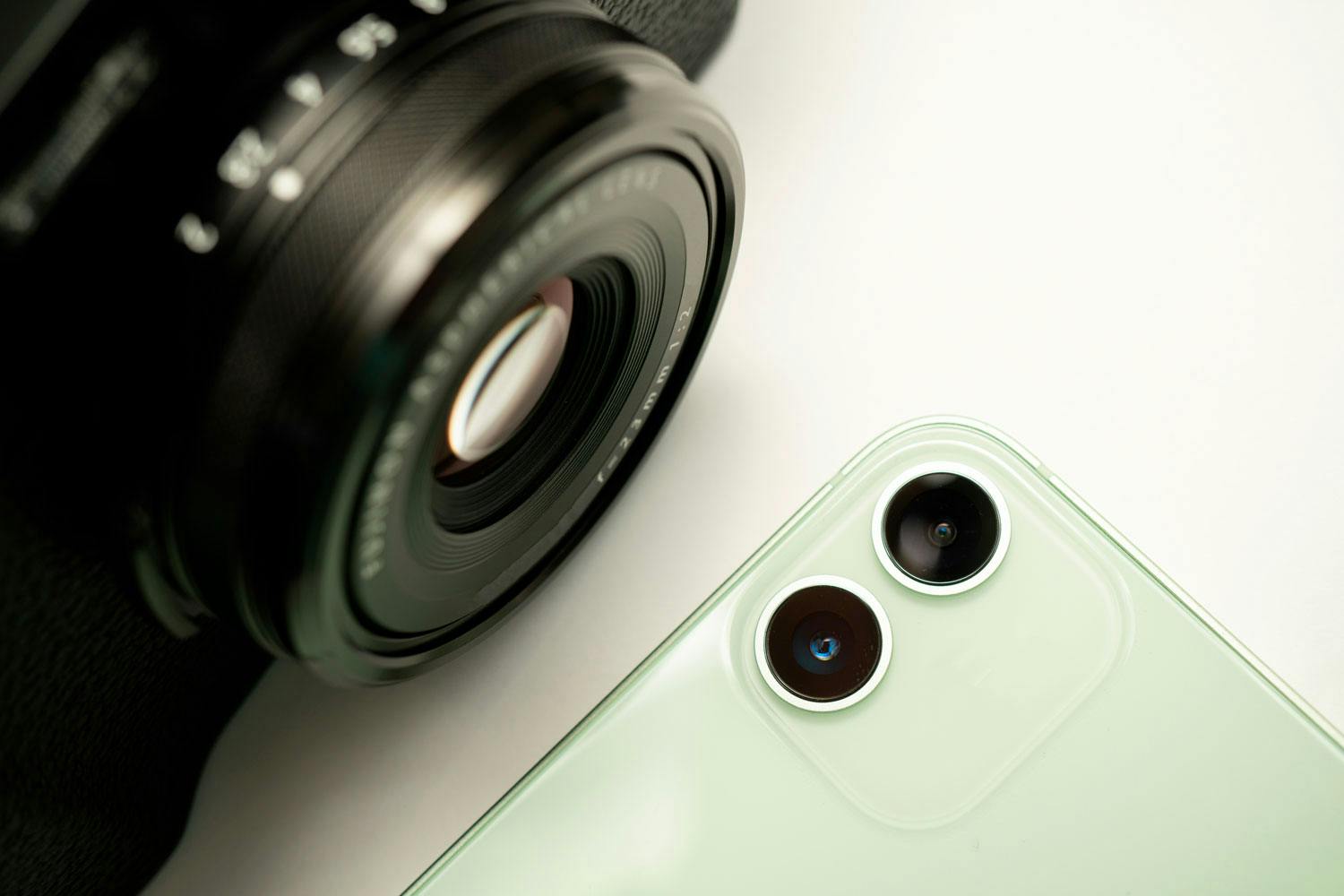 Mobil og speilløst systemkamera. Objektivet på et speilløst systemkamera er mye bedre enn det smarttelefonen har.